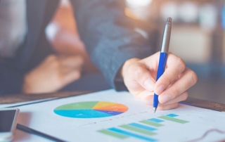 Accountant viewing reports on desk and holding a pen